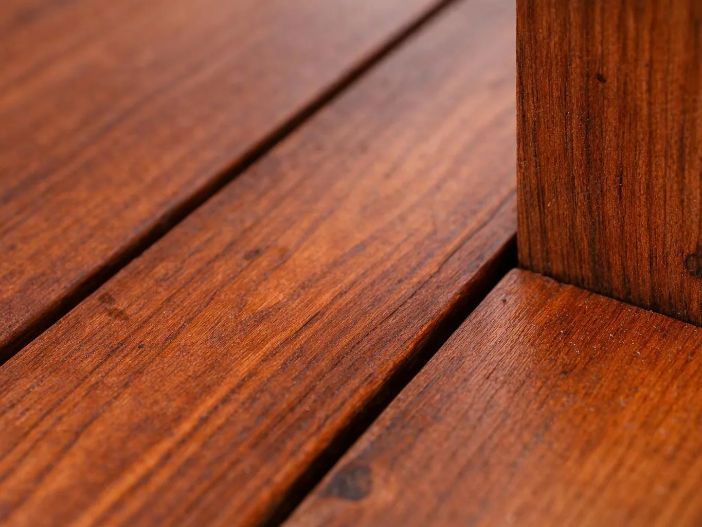 Close-up of stained wooden planks meeting a vertical post with visible grain and seams