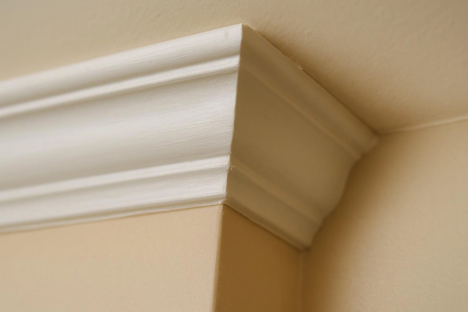 White crown molding meets beige walls at an interior ceiling corner